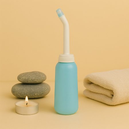 Lichtblauwe vaginale douche met gebogen tuit, naast een handdoek